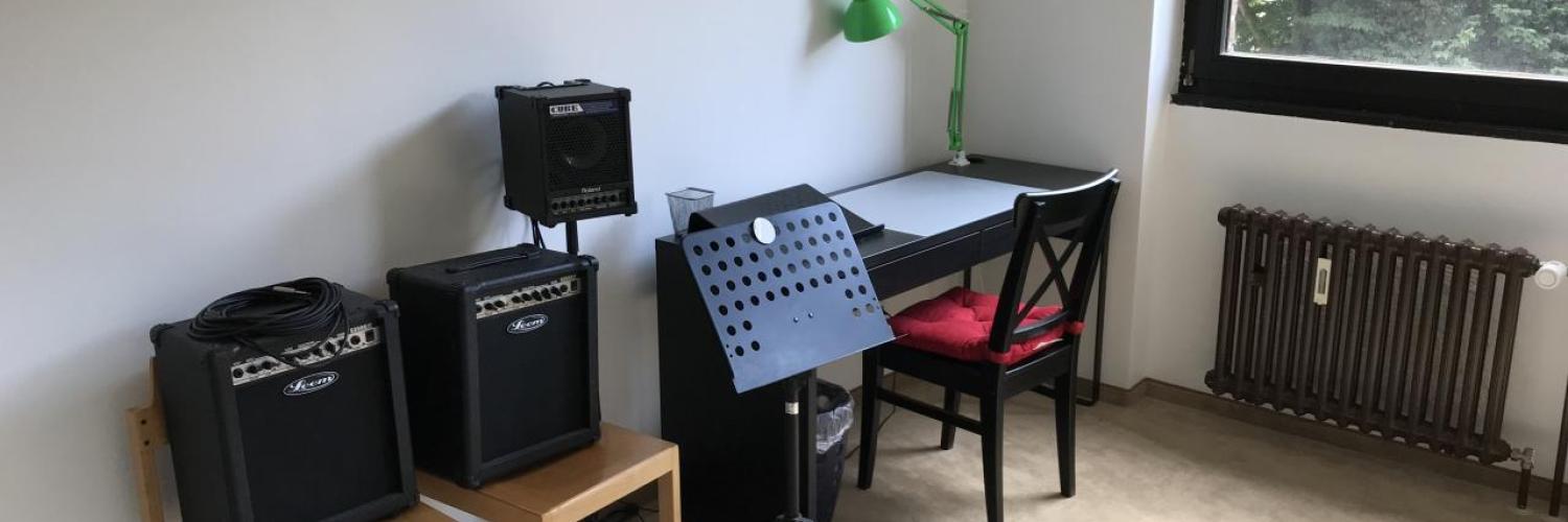 Gitarrenunterrichtsraum mit zwei Verstärkern und Notenständer am Fenster
