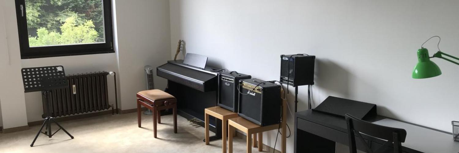 Unterrichtsraum mit Digitalpiano, Gitarrenverstärker und Notenständer